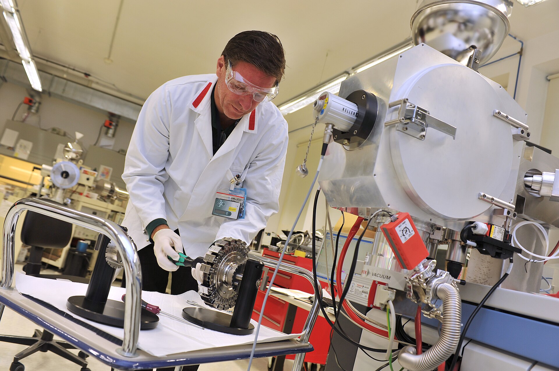Analytical technician reviewing data beside a mass spectrometer in a laboratory