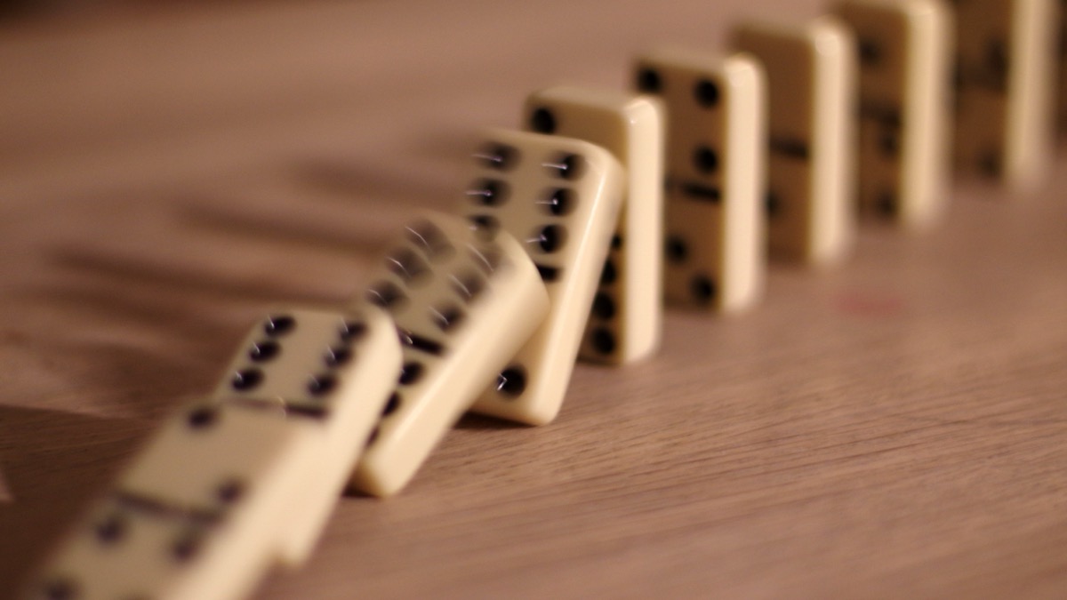 A line of dominoes falling, representing cascading failures in an agentic scientific workflow