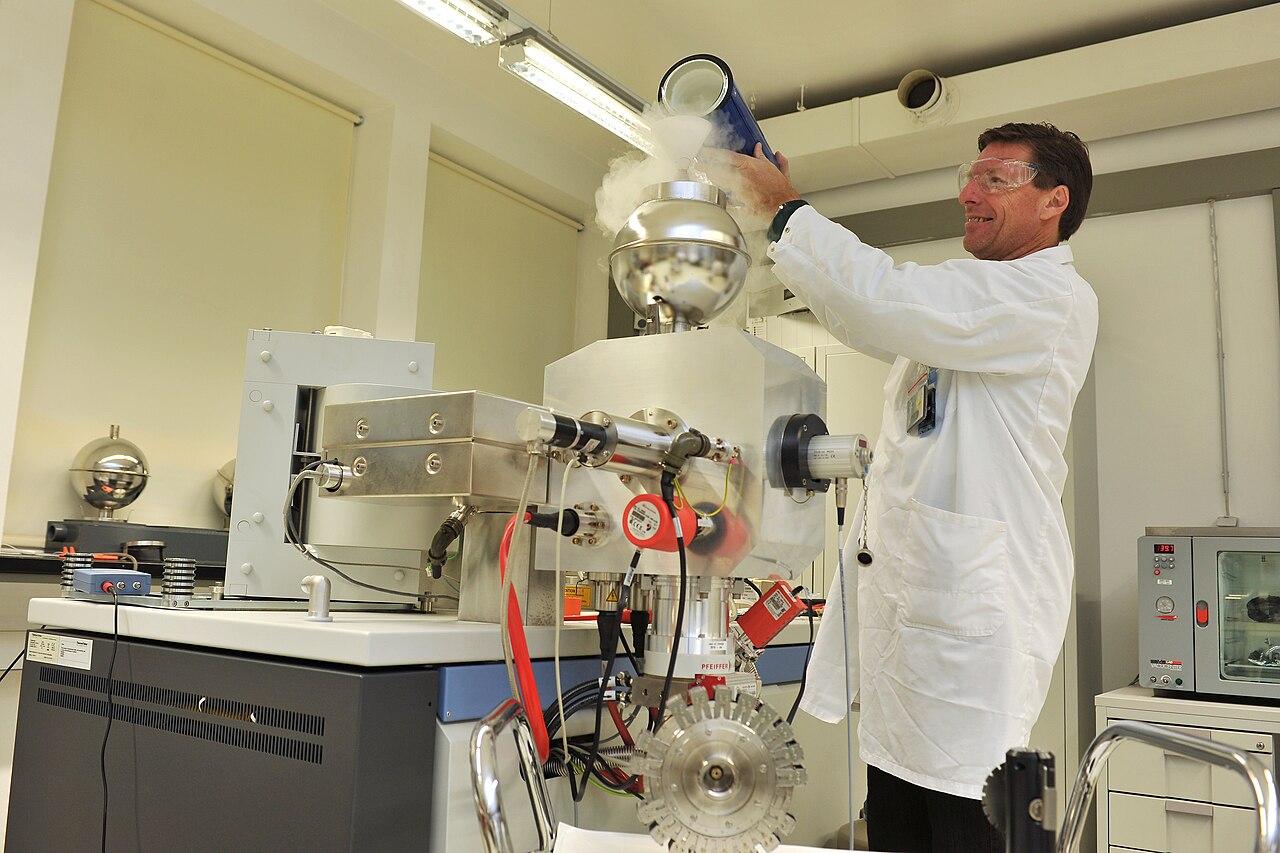 Analytical chemist working beside a mass spectrometer in a laboratory used for compound identification